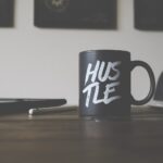 black and white Hustle-printed ceramic mug on table